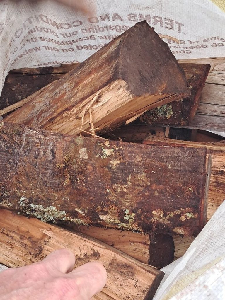 Wattle logs with lichen-covered bark packed in a sack for a braai wood order
