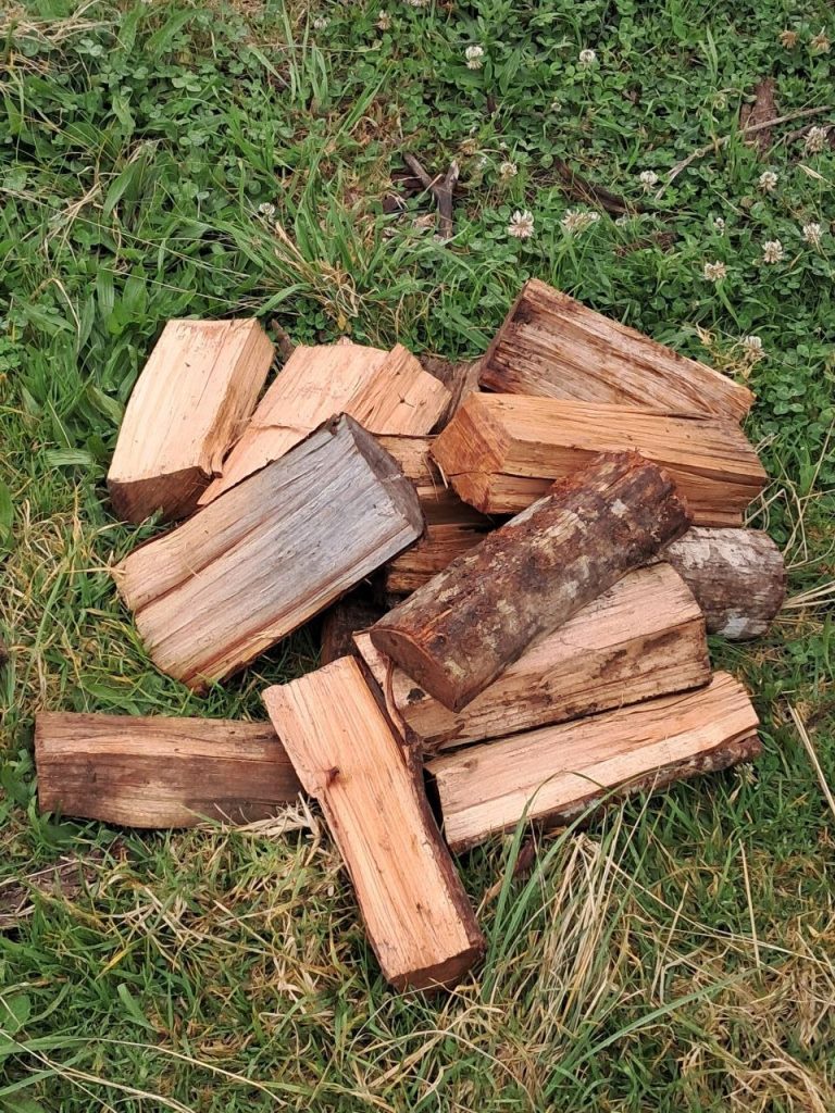 A small stack of split wattle braai wood on the grass, ready for the fire